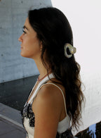 Woman with a hair clip against a light-colored wall