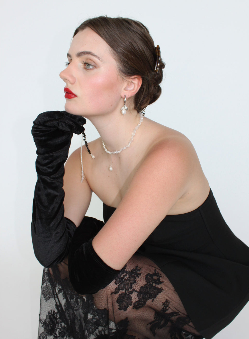 Woman wearing a black dress with floral details and a black glove, against a white background