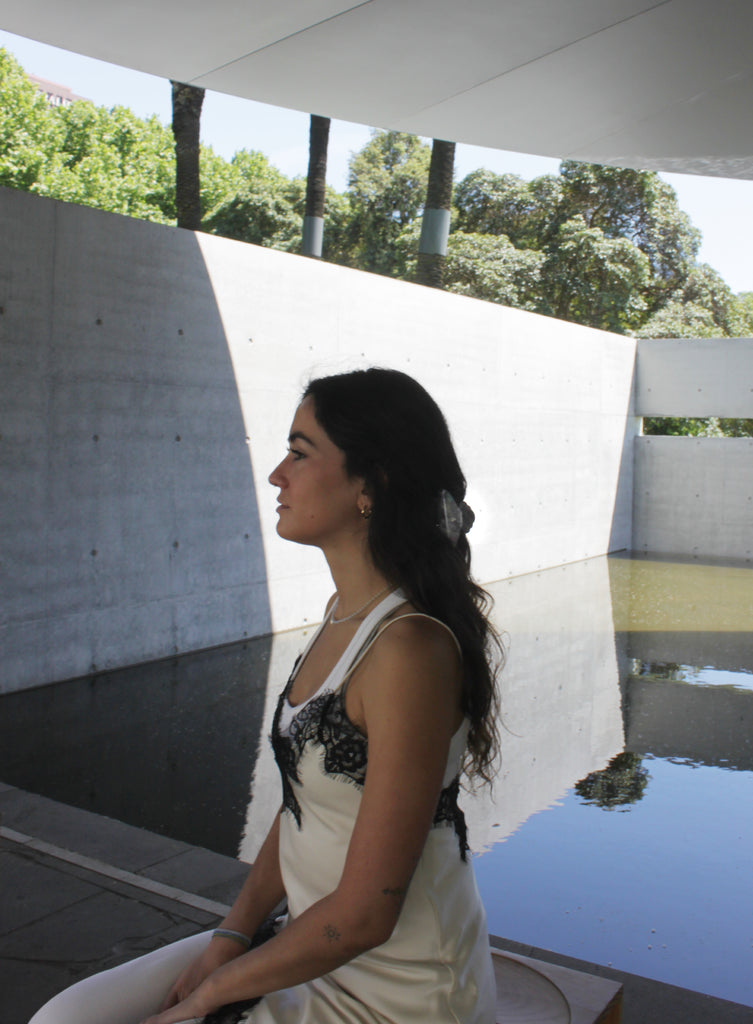 Woman with long dark hair standing against a light-colored wall with hair claw