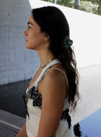 Woman with a green hair claw standing outdoors near a pool.