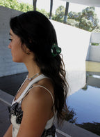 Woman with a green hair claw standing outdoors near a pool.