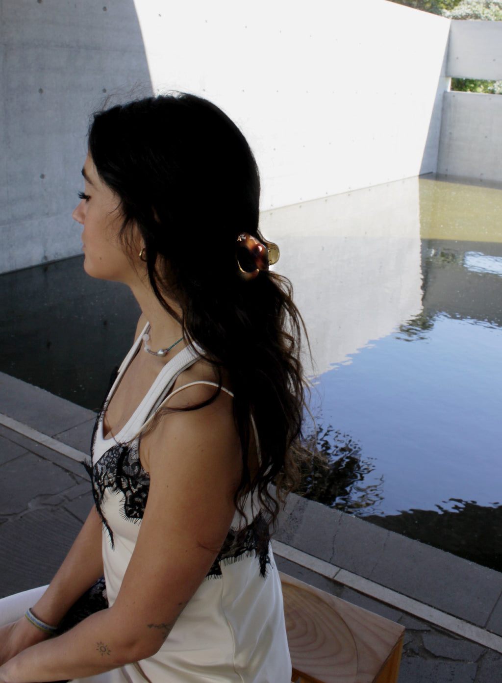 Woman sitting by a pool wearing brown hair claw