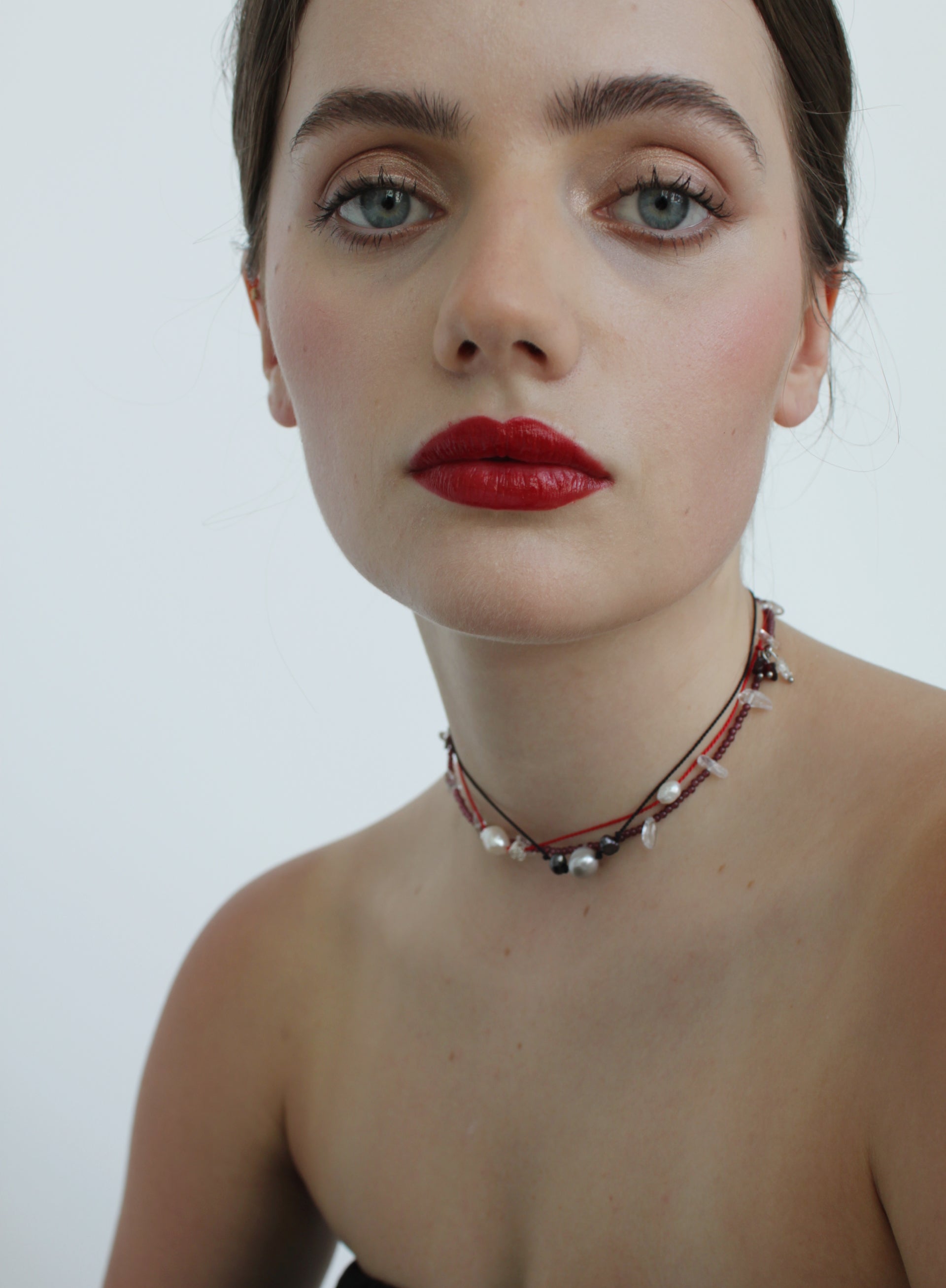 Woman wearing a choker necklace against a plain background
