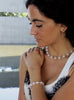 Woman wearing a rose quartz necklace and pearl bracelet with a blurred background