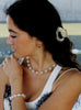 Woman wearing a rose quartz necklace and pearl bracelet with a blurred background