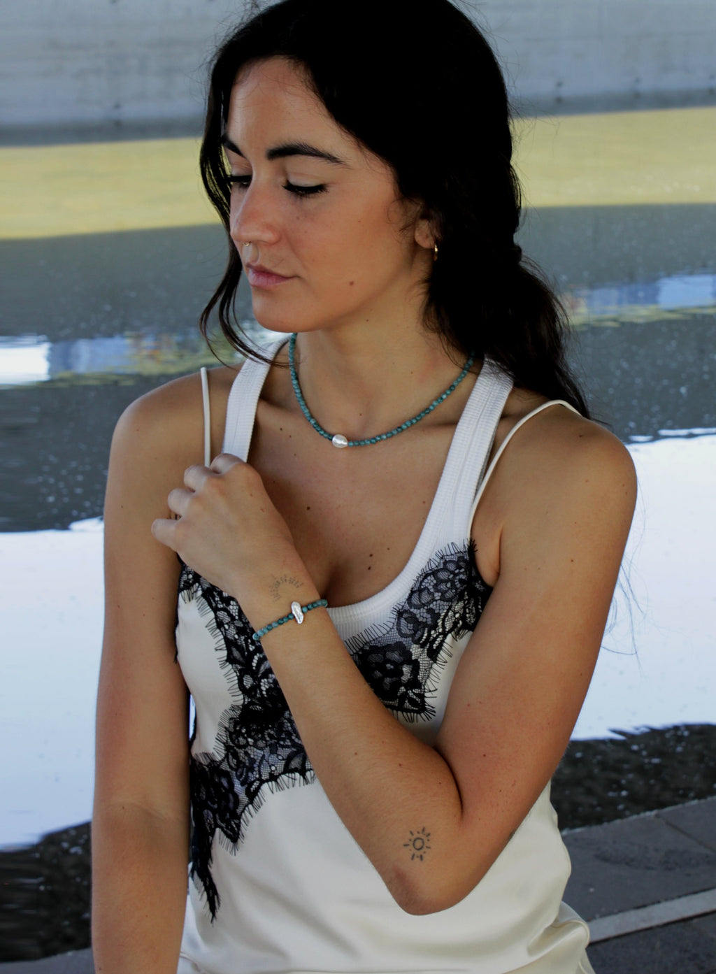 Woman wearing a white tank top with blue beaded pearl necklace and bracelet