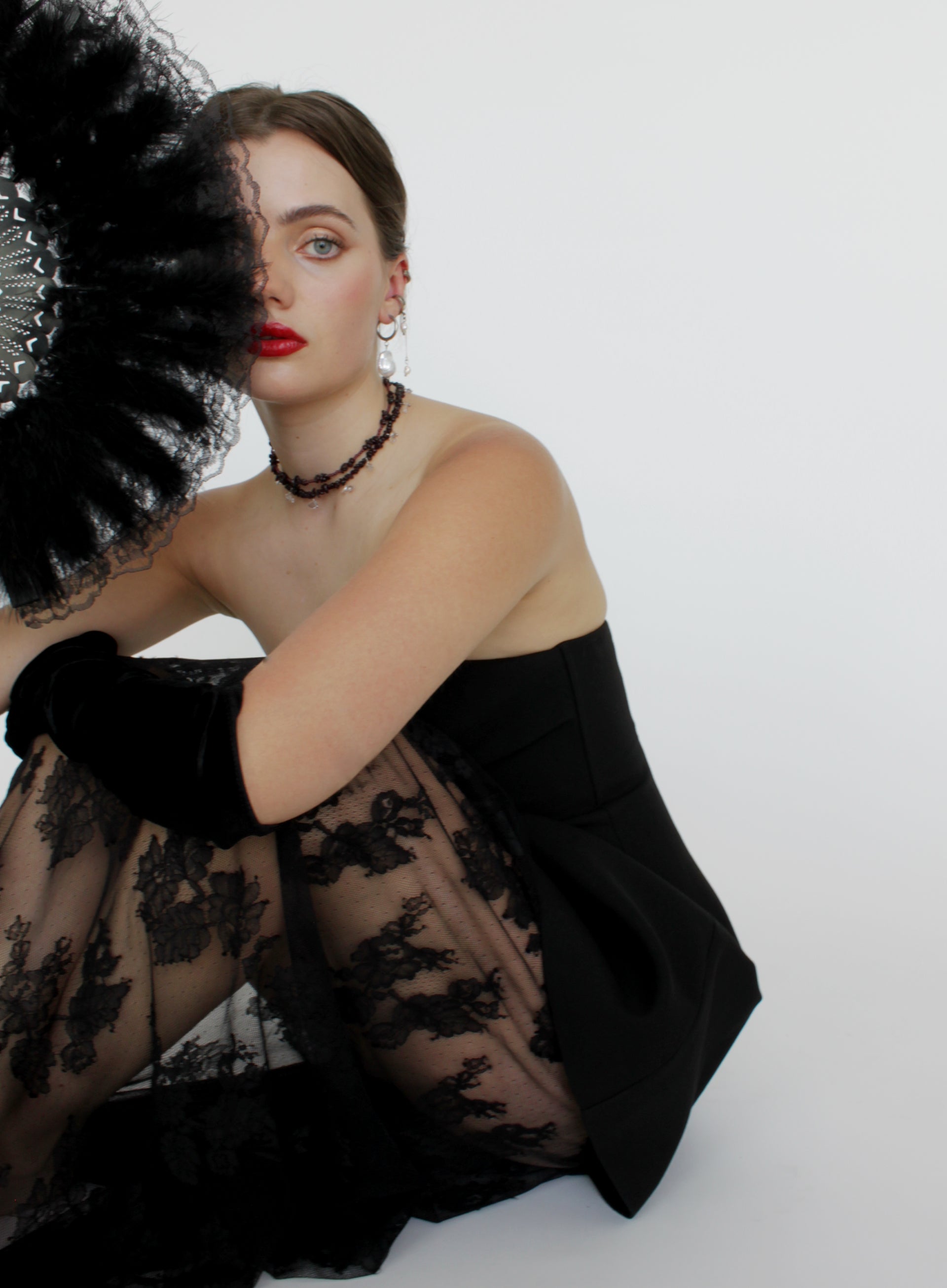 Woman wearing a black lace dress with a white background