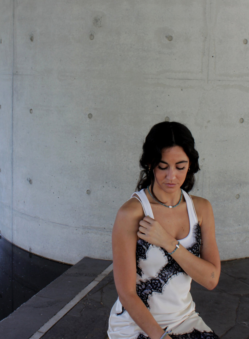 Woman wearing a white tank top with blue beaded pearl necklace and bracelet