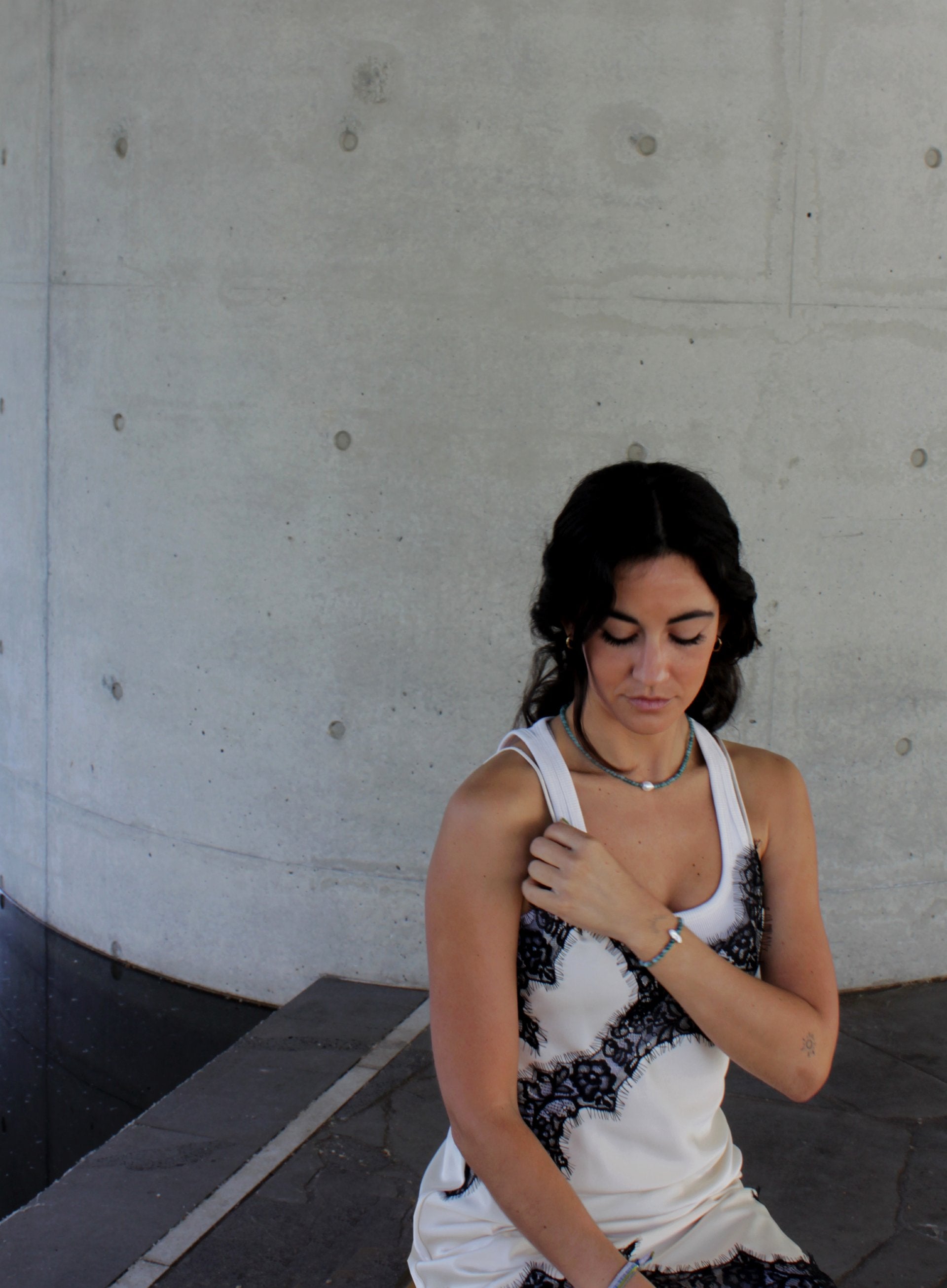 Woman wearing a white tank top with blue beaded pearl necklace and bracelet