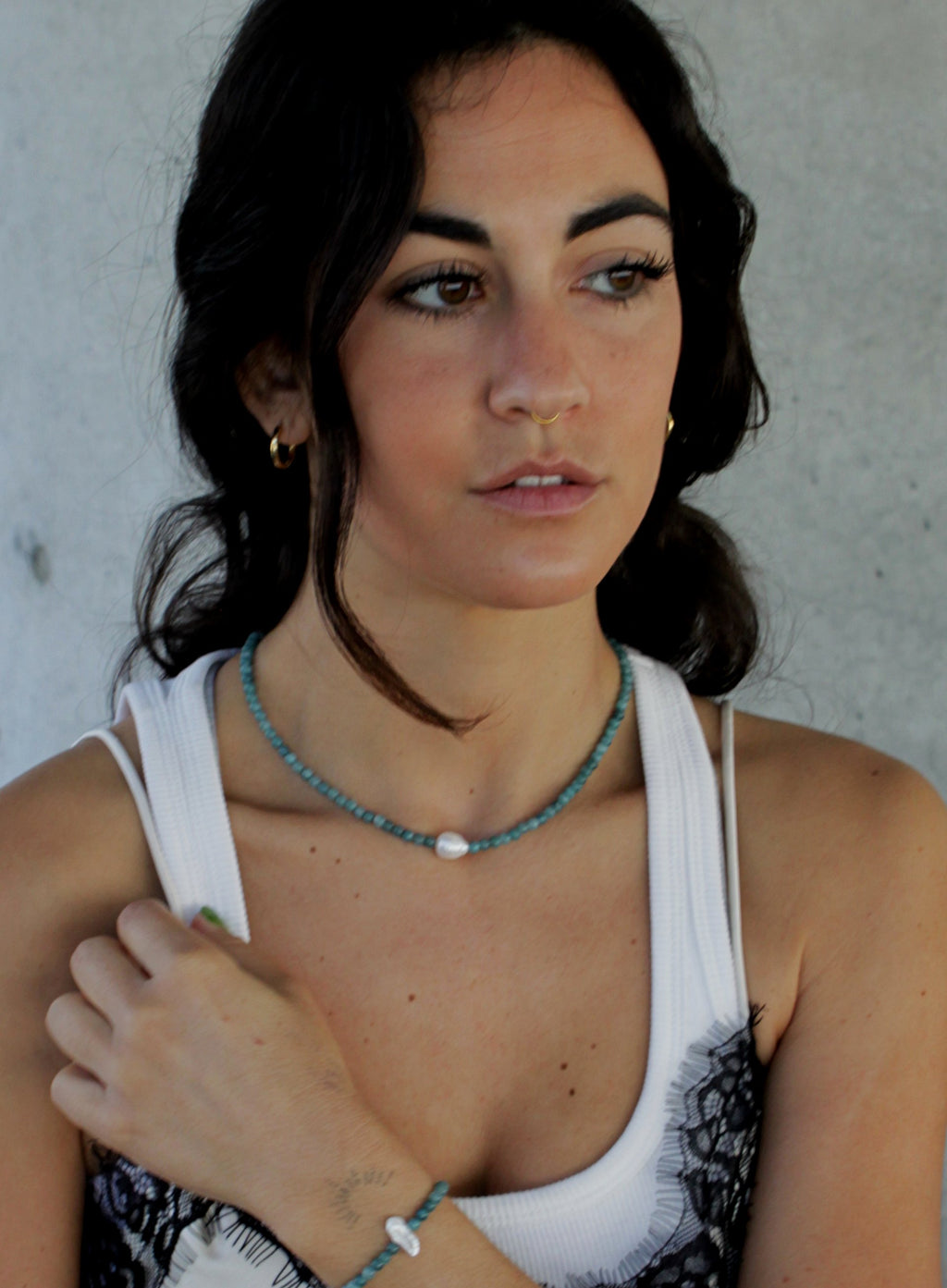 Woman wearing a white tank top with blue beaded pearl necklace and bracelet