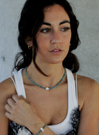 Woman wearing a white tank top with blue beaded pearl necklace and bracelet