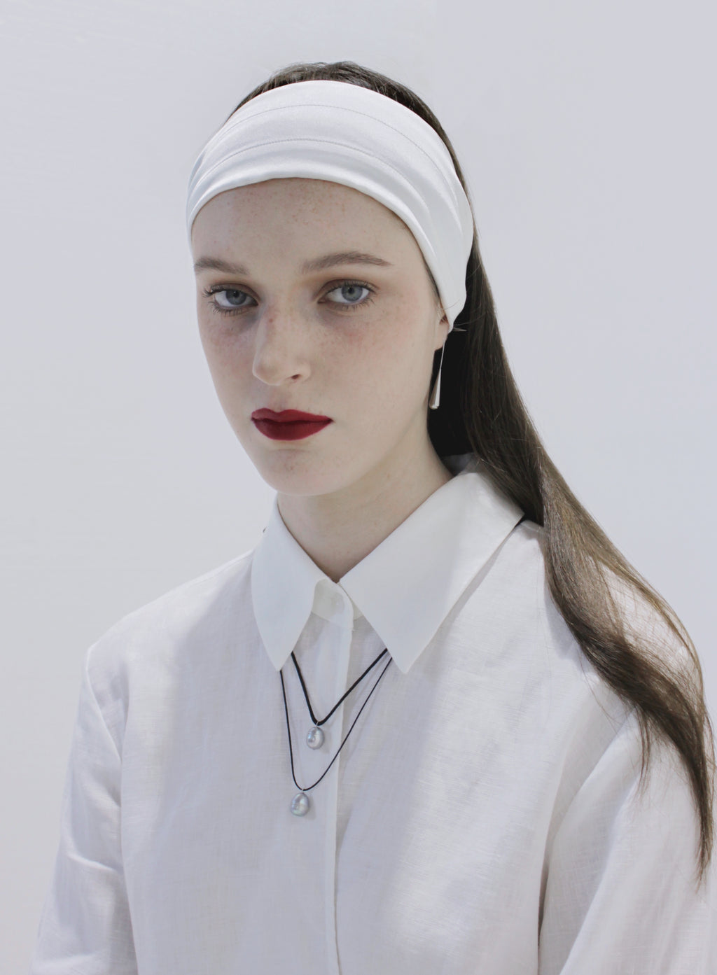 Woman wearing a white headband and white outfit against a plain background