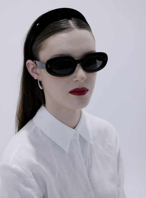 Person wearing black sunglasses and a black headband against a white background