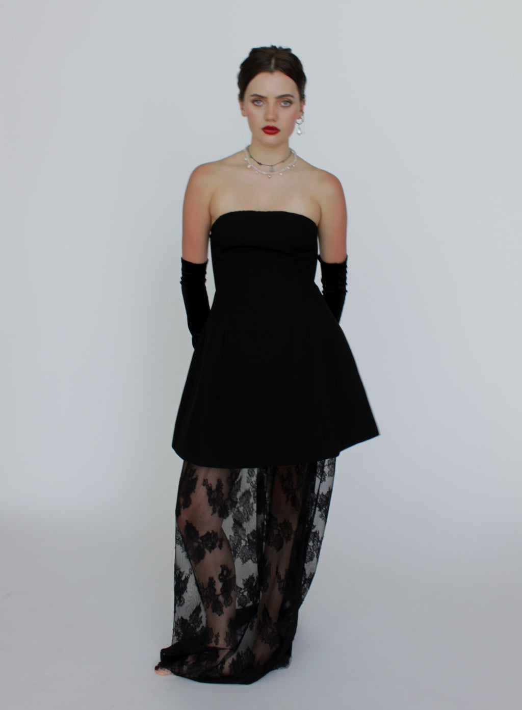 Woman wearing a black strapless top and sheer dress with floral patterns on a white background