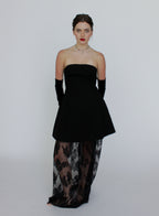 Woman wearing a black strapless top and sheer dress with floral patterns on a white background