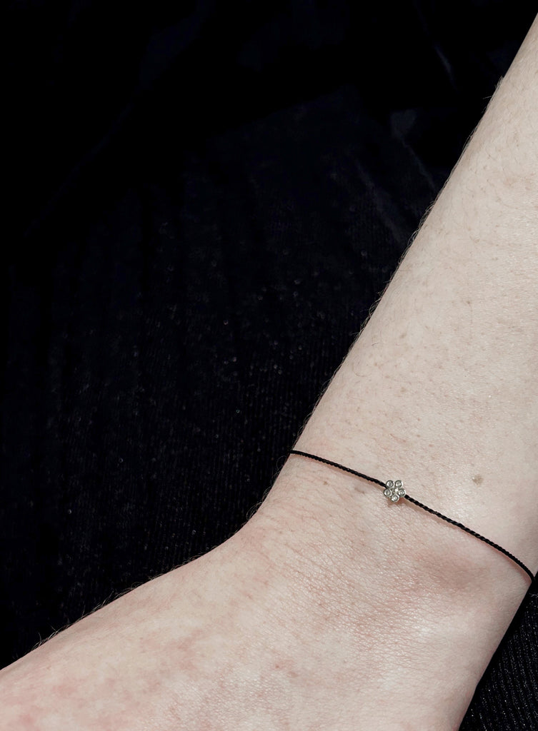black silk cord bracelet with silver petal charm on hand