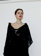 Woman wearing a black outfit with intricate designs on a white background