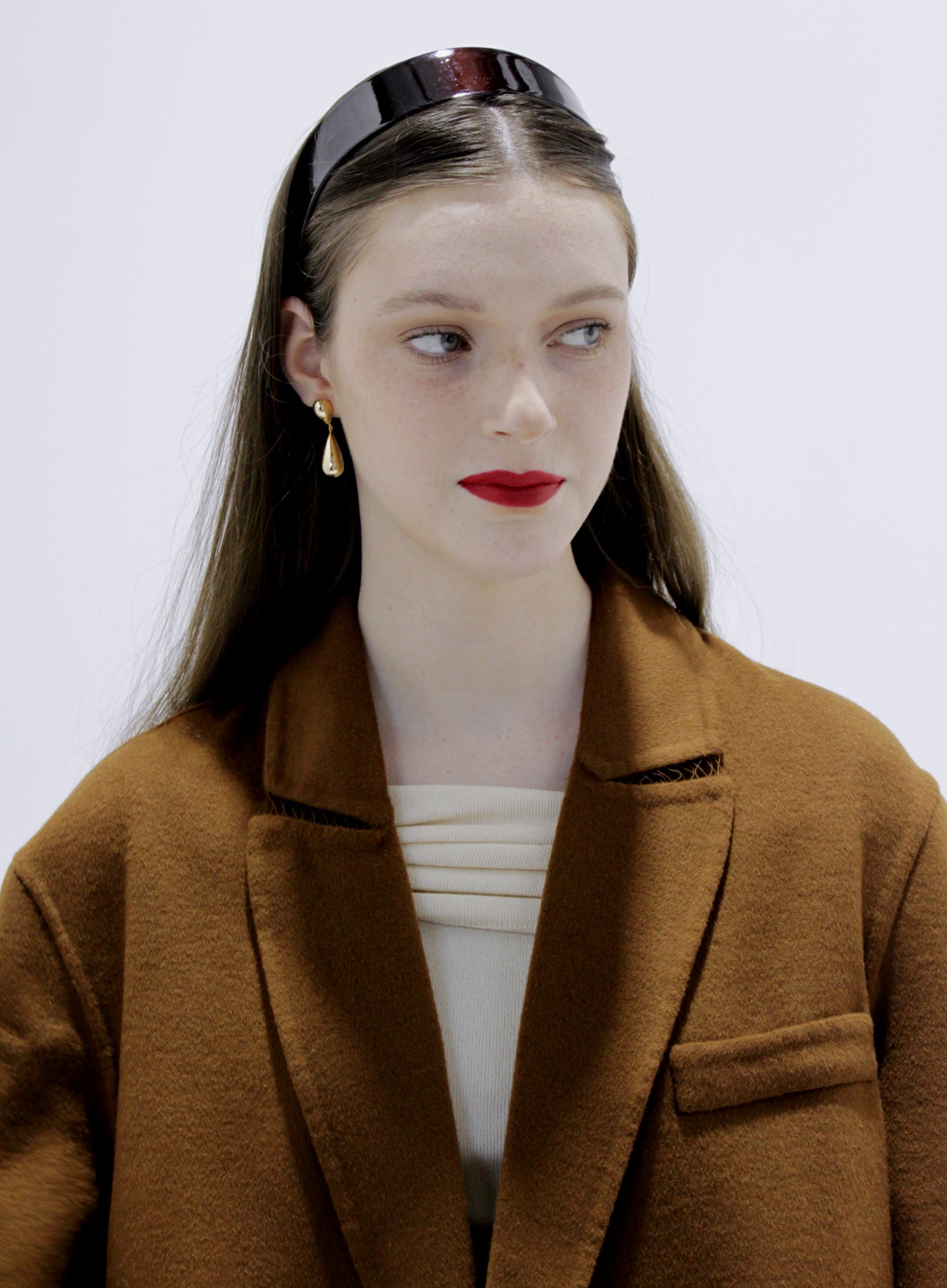 Woman wearing a brown coat with gold earrings